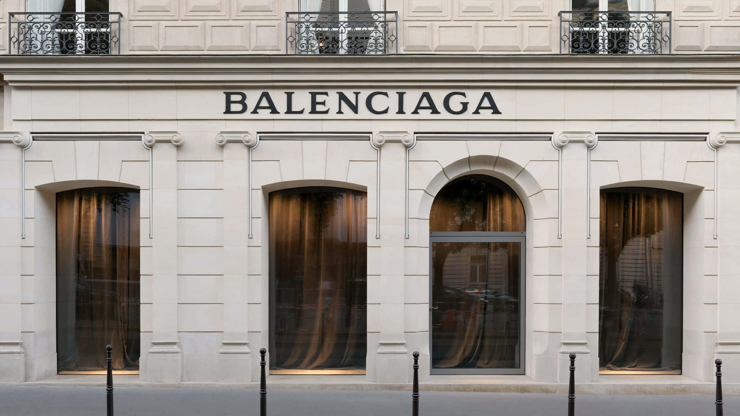 體驗奢華生活，盡在Balenciaga 壁紙 — 在明亮的日光下，純白色的 Balenciaga 精品店外牆，配有拱形窗戶和優雅的鐵藝陽台。