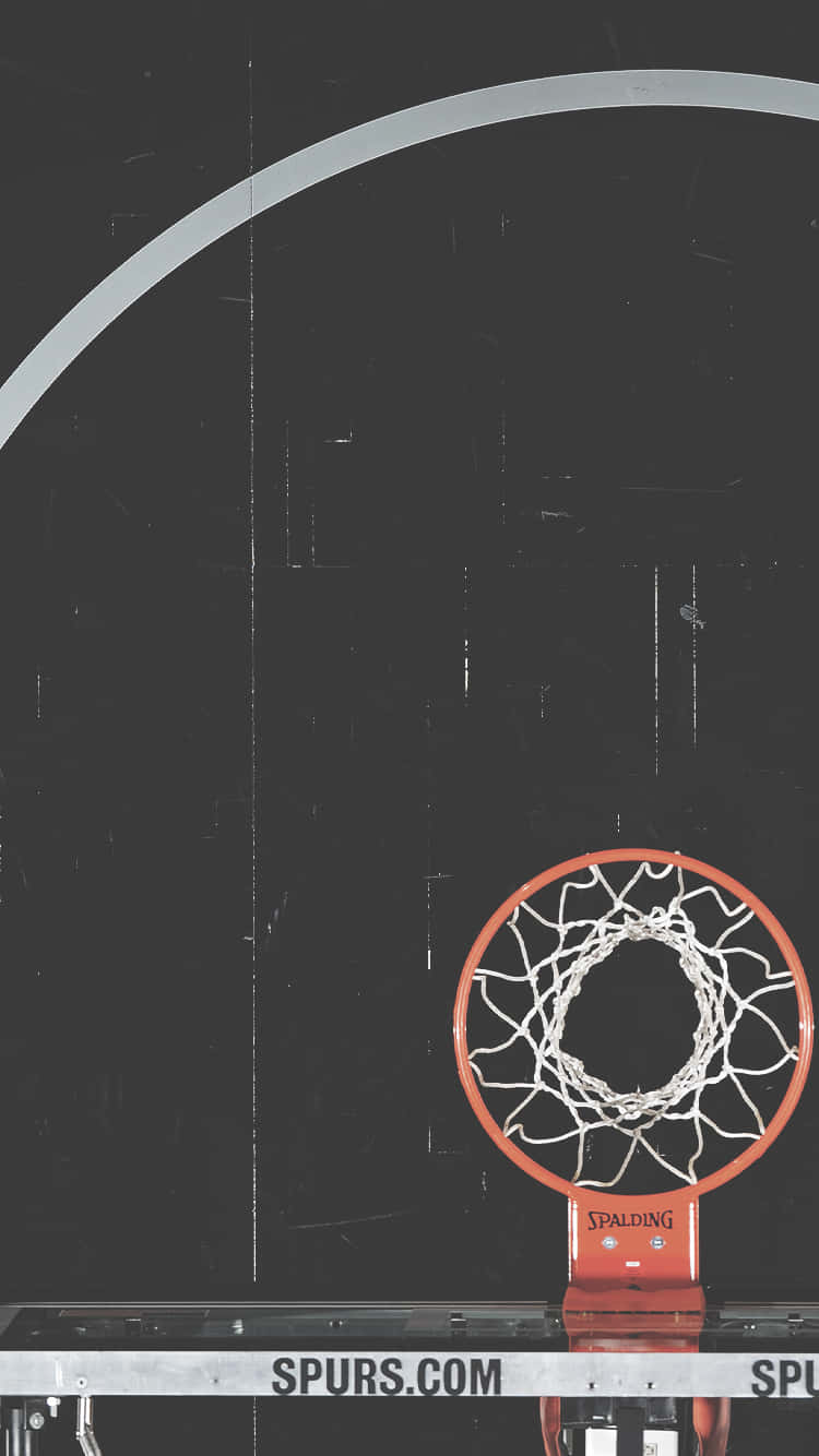 在深色球場上帶有Spurs.com品牌的籃球框和網。