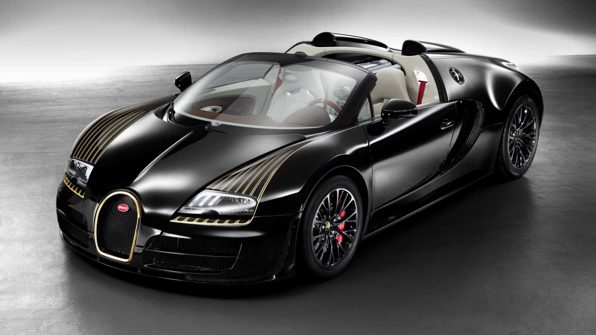黑色Bugatti Veyron Grand Sport，帶有金色飾邊和紅色制動器，在工作室中。