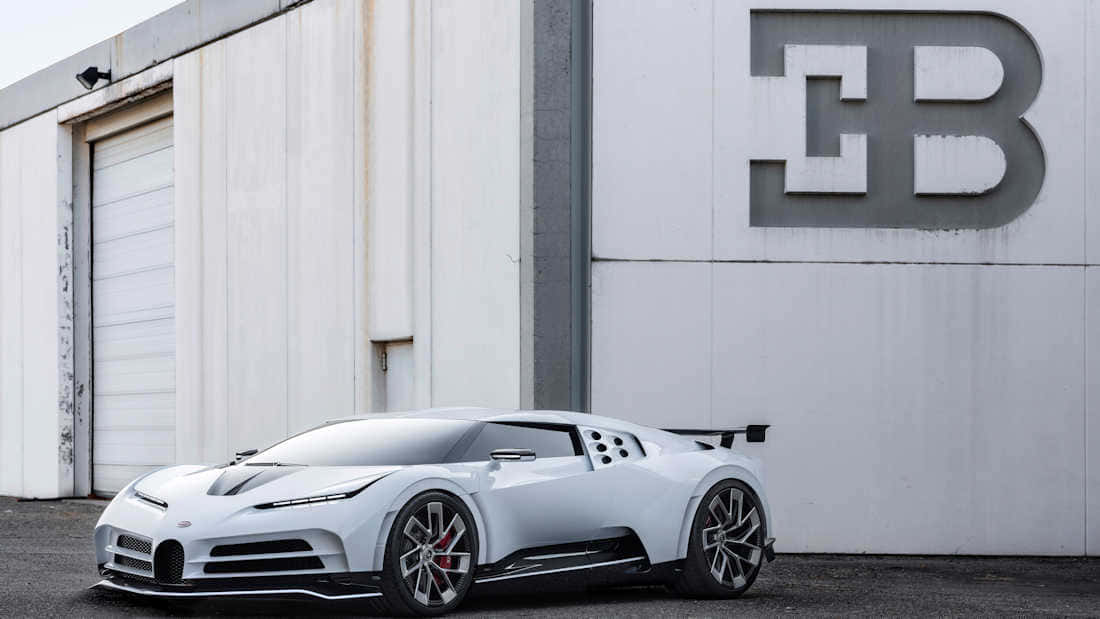 白色Bugatti超級跑車停在帶有大型B標誌的工廠外。