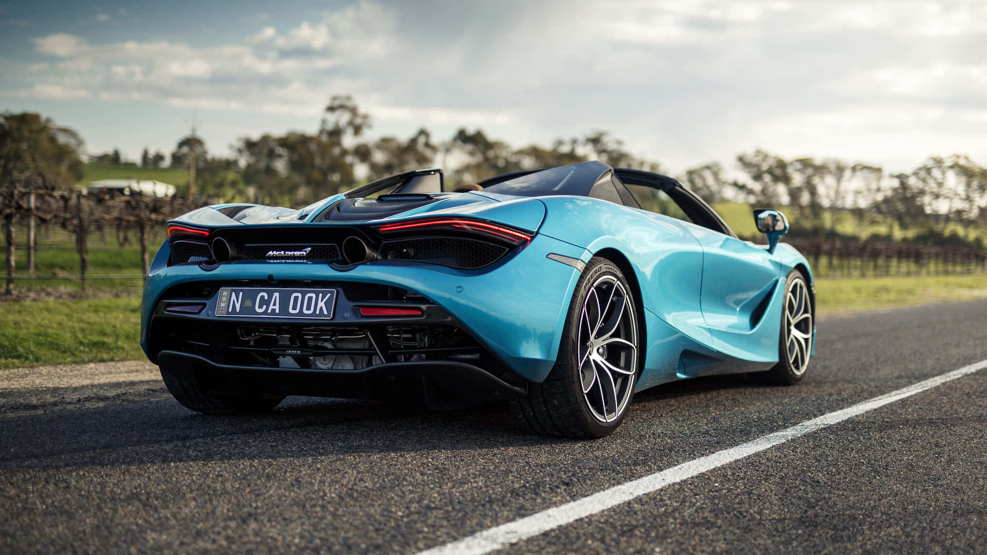 日落時分，青綠色McLaren 720S Spider在葡萄園附近的鄉間小路上行駛。