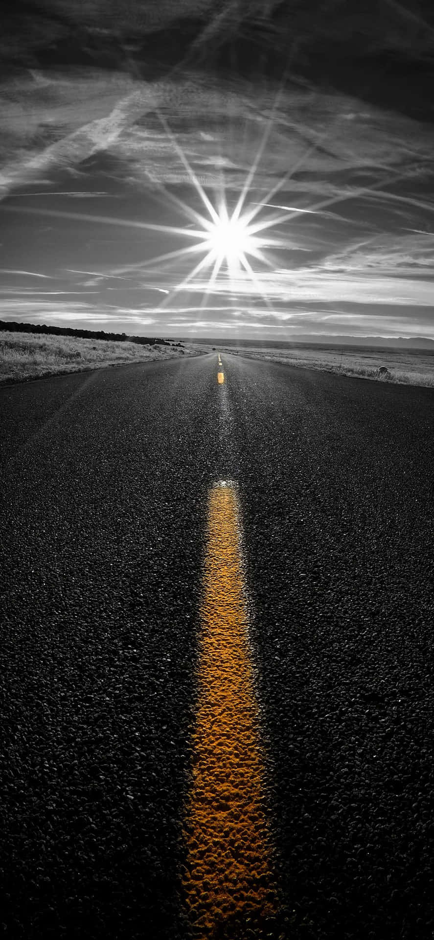 在明亮太陽下的一條長直道路，帶有黃色中心線。