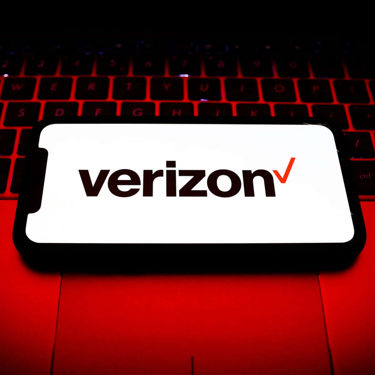 智能手機在紅色照亮的筆記本電腦鍵盤上顯示Verizon標誌。