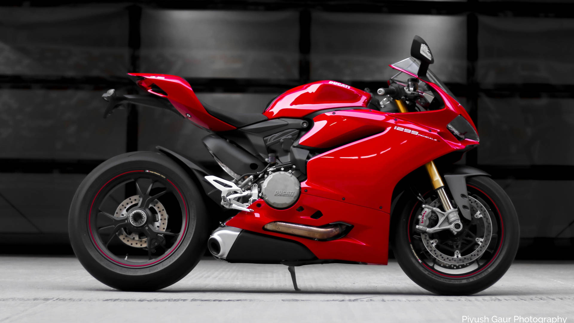 一輛紅色Ducati運動電單車，在攝影棚中帶有黑色和金色細節。