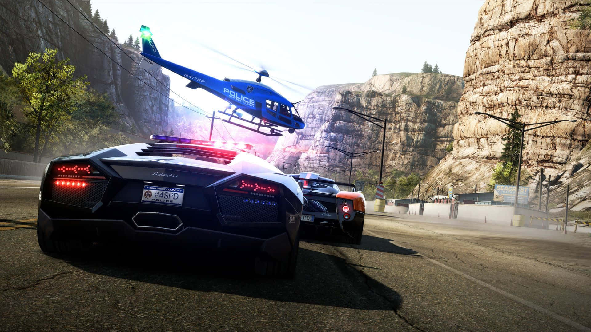 體驗極致賽車快感，盡在最佳《Need For Speed》 壁紙 — 一架藍色警用直升機盤旋在一輛黑色林寶堅尼Aventador上空，該車正被另一輛警車在山路上追捕。