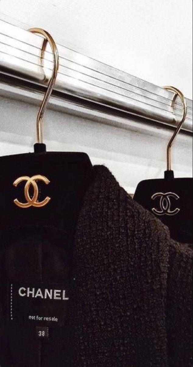 黑色 Chanel 服裝掛在金色衣架上，帶有可見的品牌標籤。