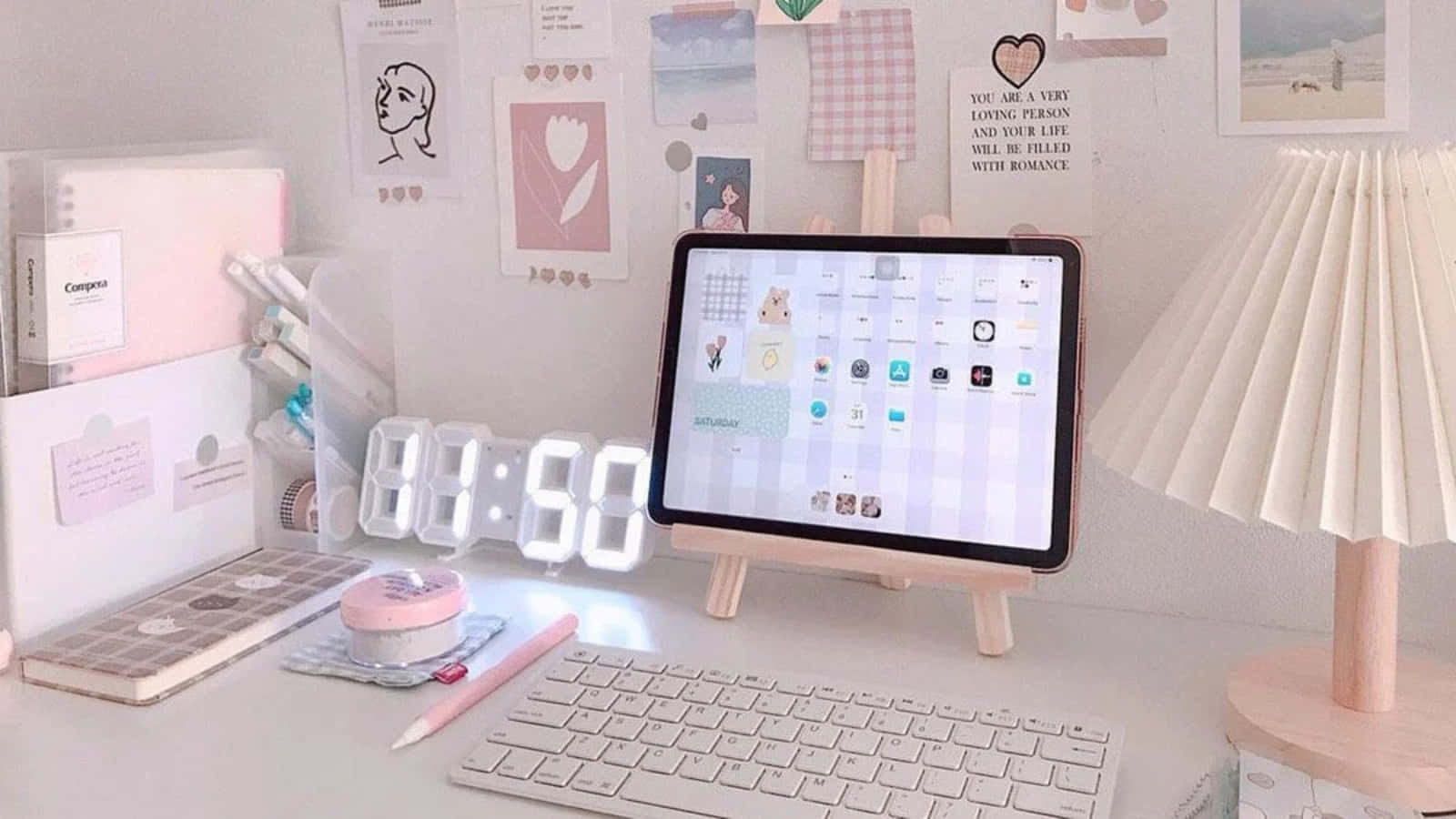 體驗現代工作空間的美學 iPad 壁紙 — 粉紅色和白色的書桌設置，配有平板鍵盤燈和裝飾牆藝術，營造舒適的學習氛圍。