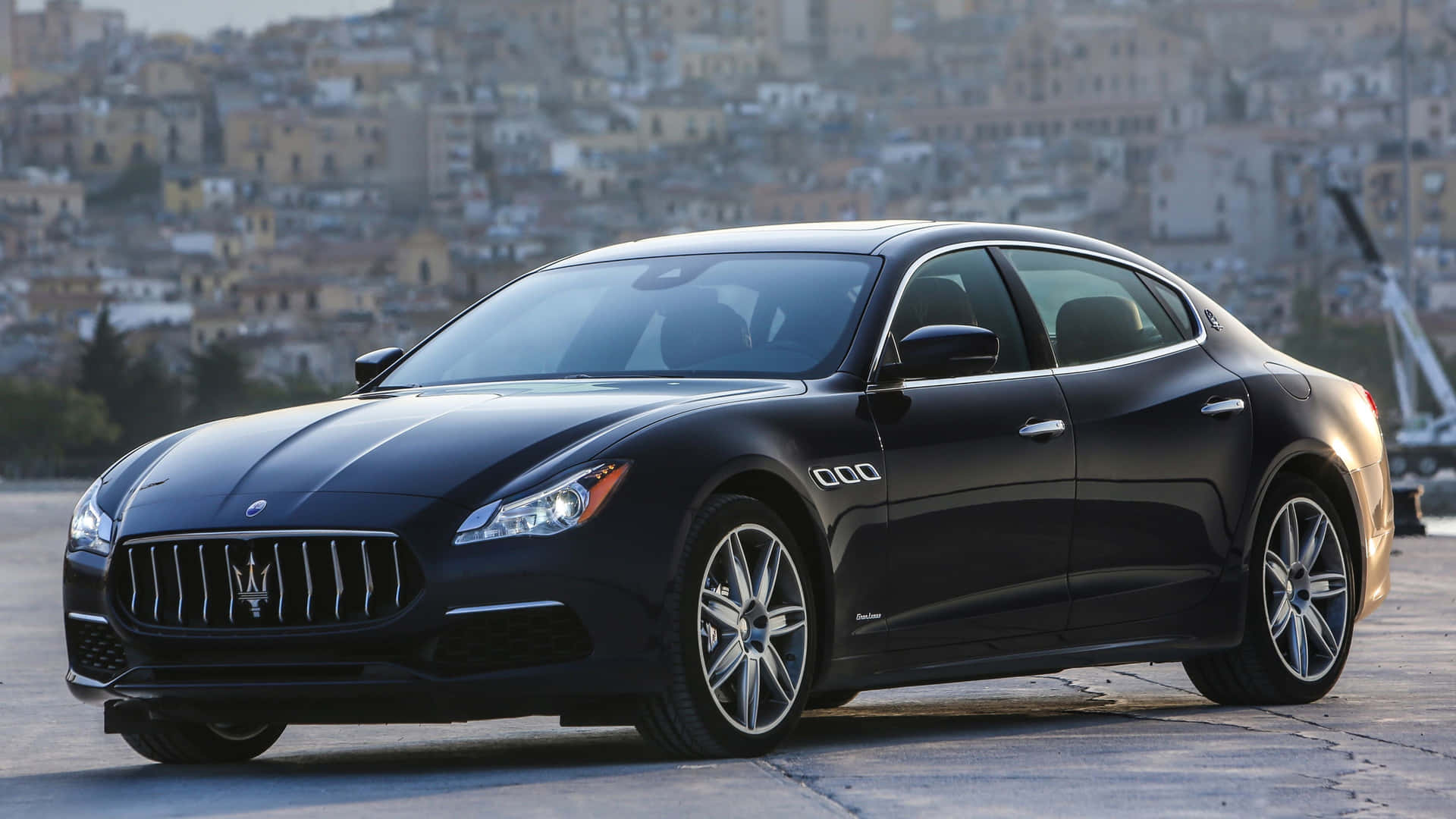 黑色瑪莎拉蒂 Quattroporte 豪華轎車在日落時停泊在城市海濱。