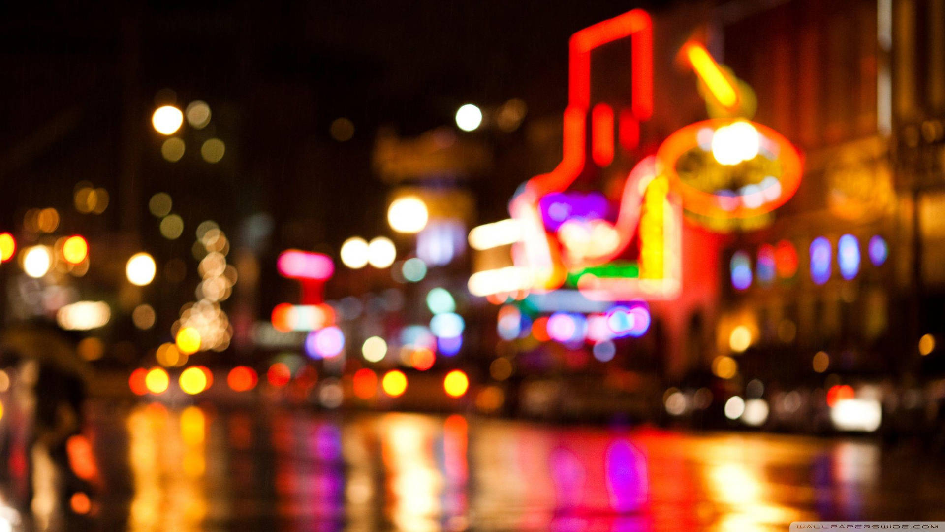 夜晚的城市燈光在潮濕的路面上模糊成色彩繽紛的散景倒影。