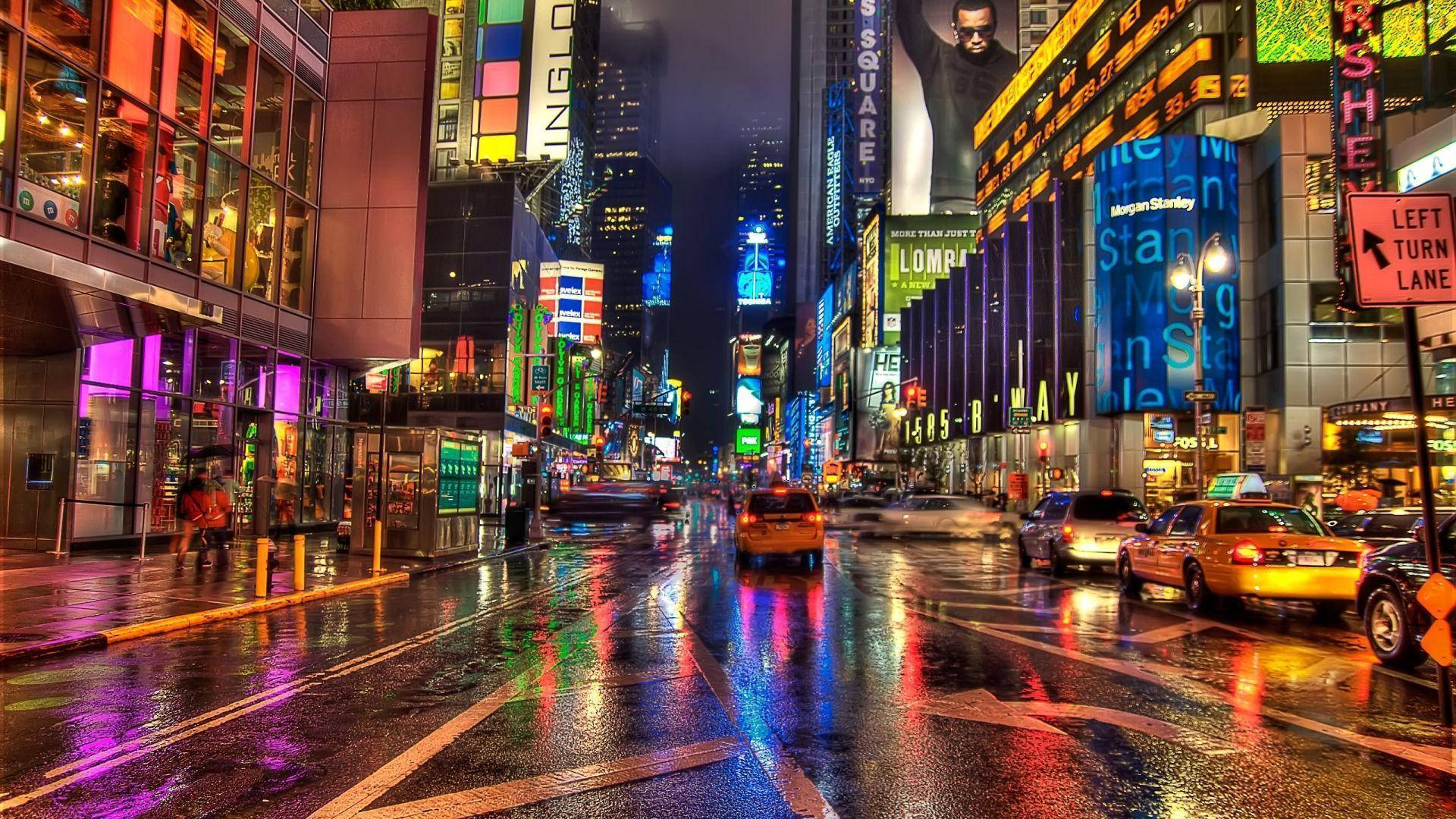 夜晚的時代廣場，濕漉漉的街道反射著霓虹燈光和黃色的士。