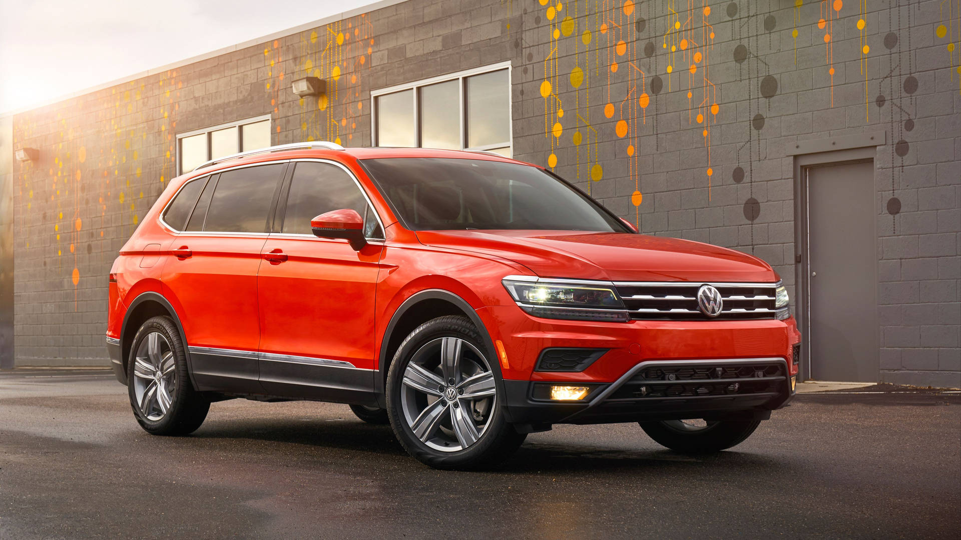 紅色福士偉根 Tiguan SUV 停在一棟現代建築前，建築上有色彩繽紛的牆壁藝術。