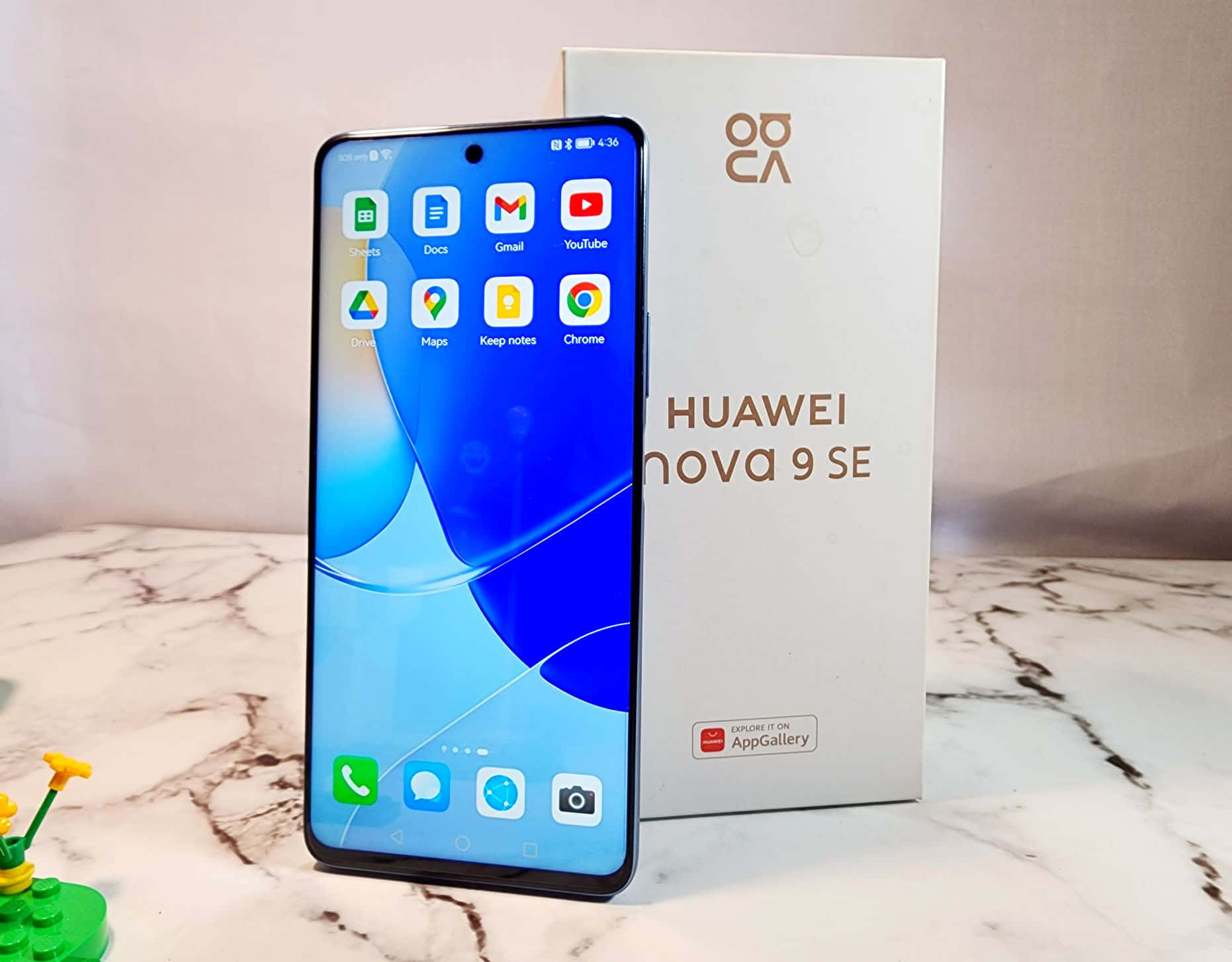 Huawei Nova 9 SE 智能手機與其盒子一起展示在大理石檯面上。