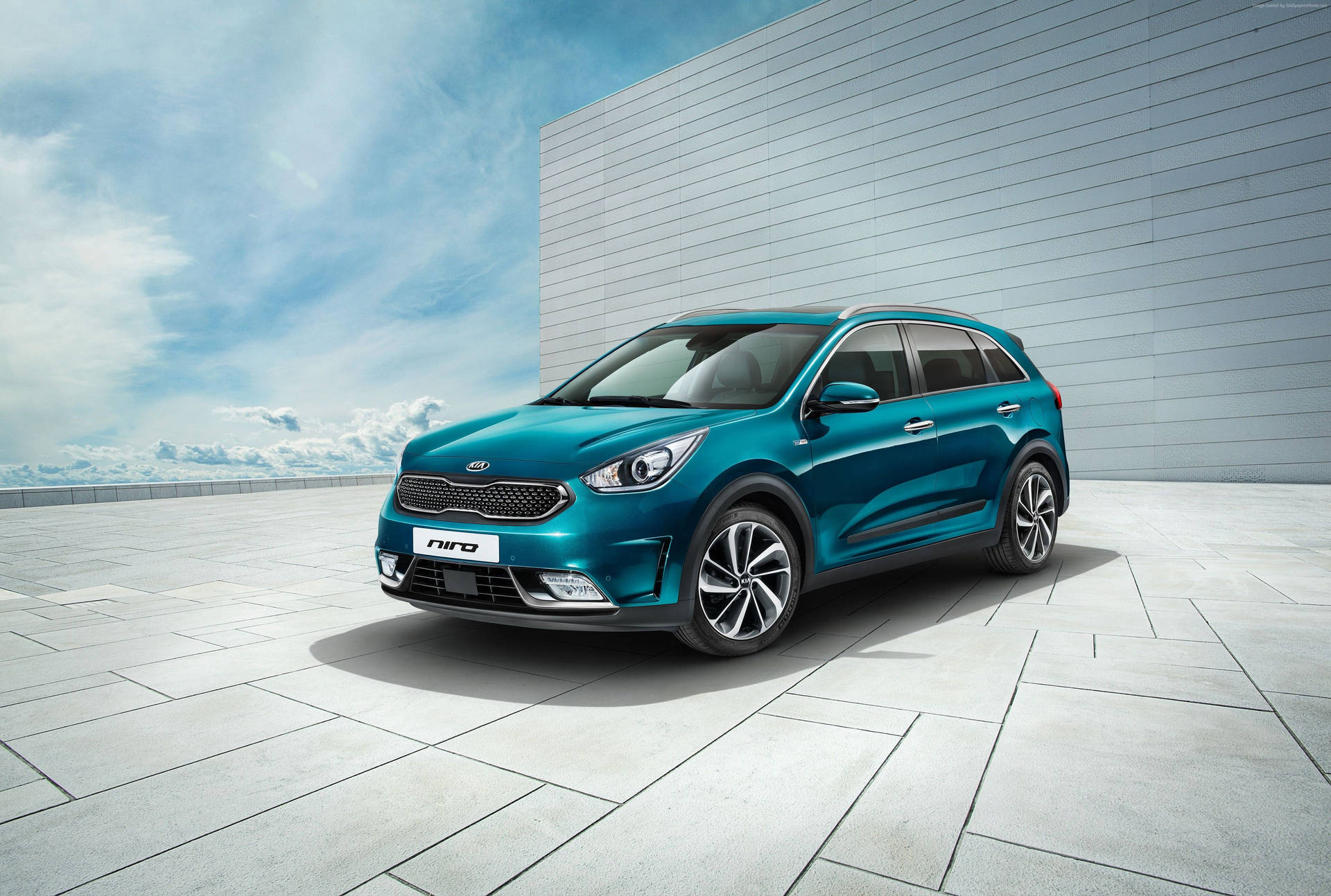 青色Kia Niro SUV停泊在屋頂上，有現代牆壁和藍天。