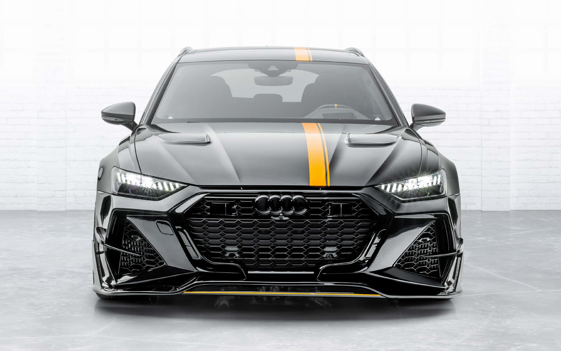 黑色奧迪RS6 Avant在白色磚牆工作室中帶有黃色賽車條紋。