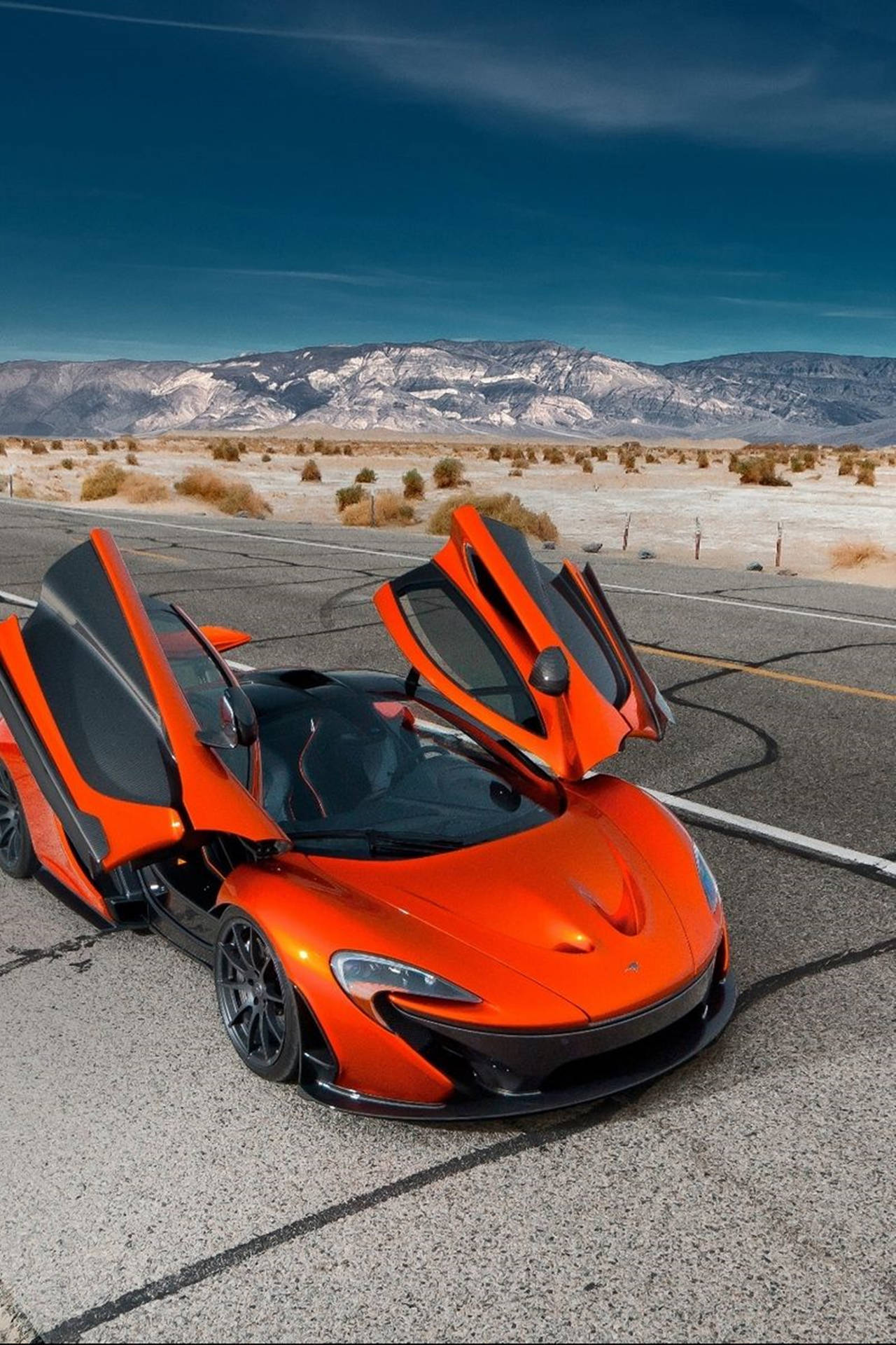 橙色McLaren跑車，車門打開，在沙漠公路上，靠近山脈，日落時分。
