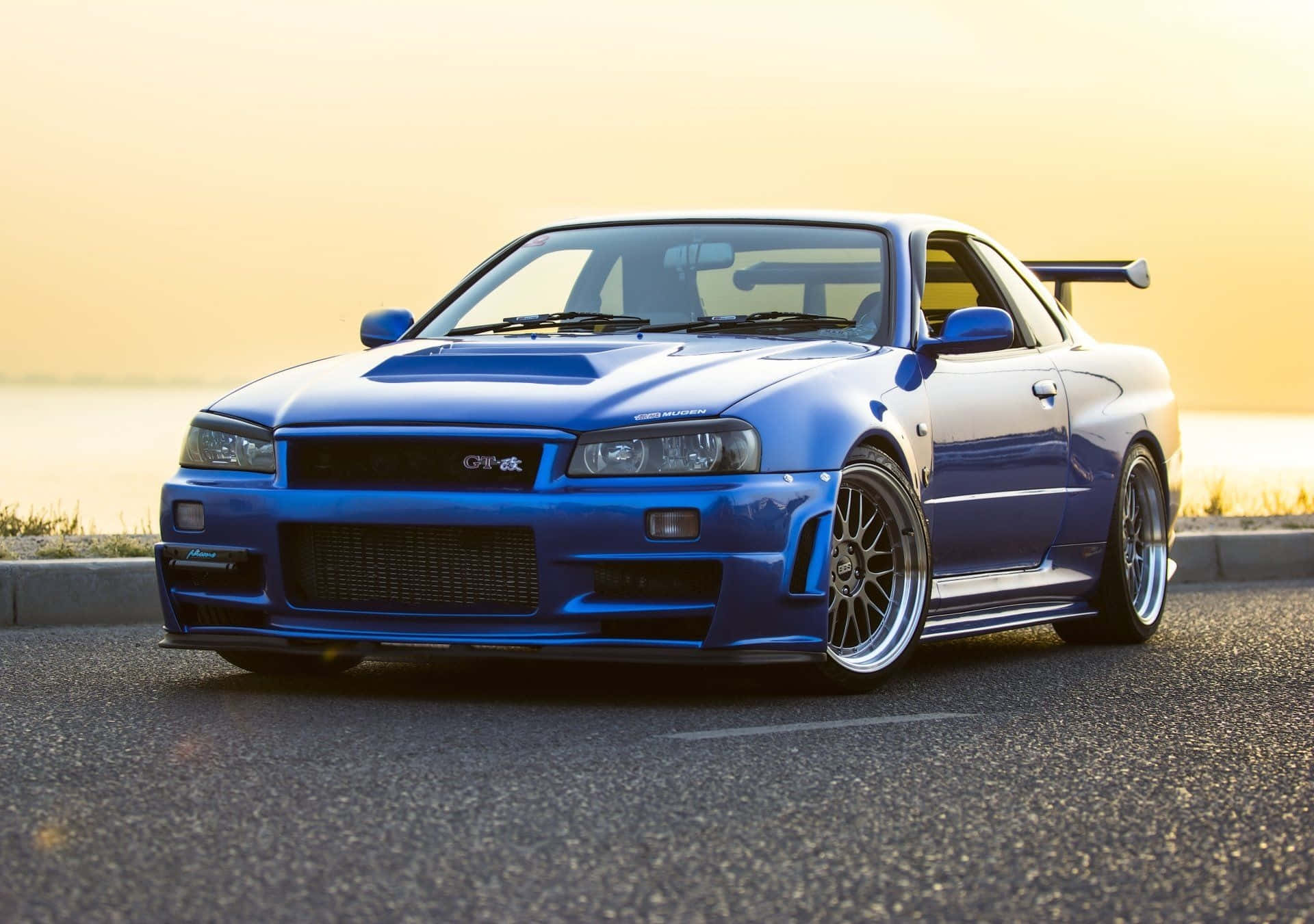 藍色日產Skyline GT-R跑車在日落時停泊在道路上。