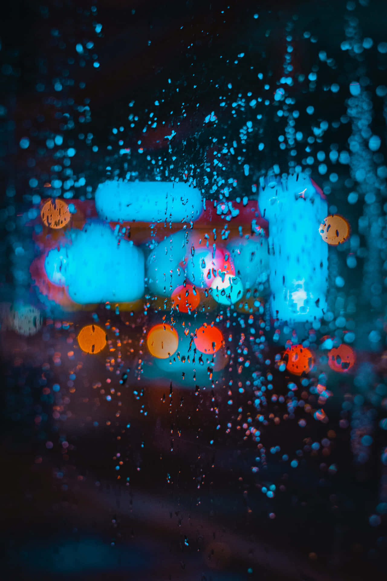 夜間窗戶上的雨滴與模糊的城市燈光