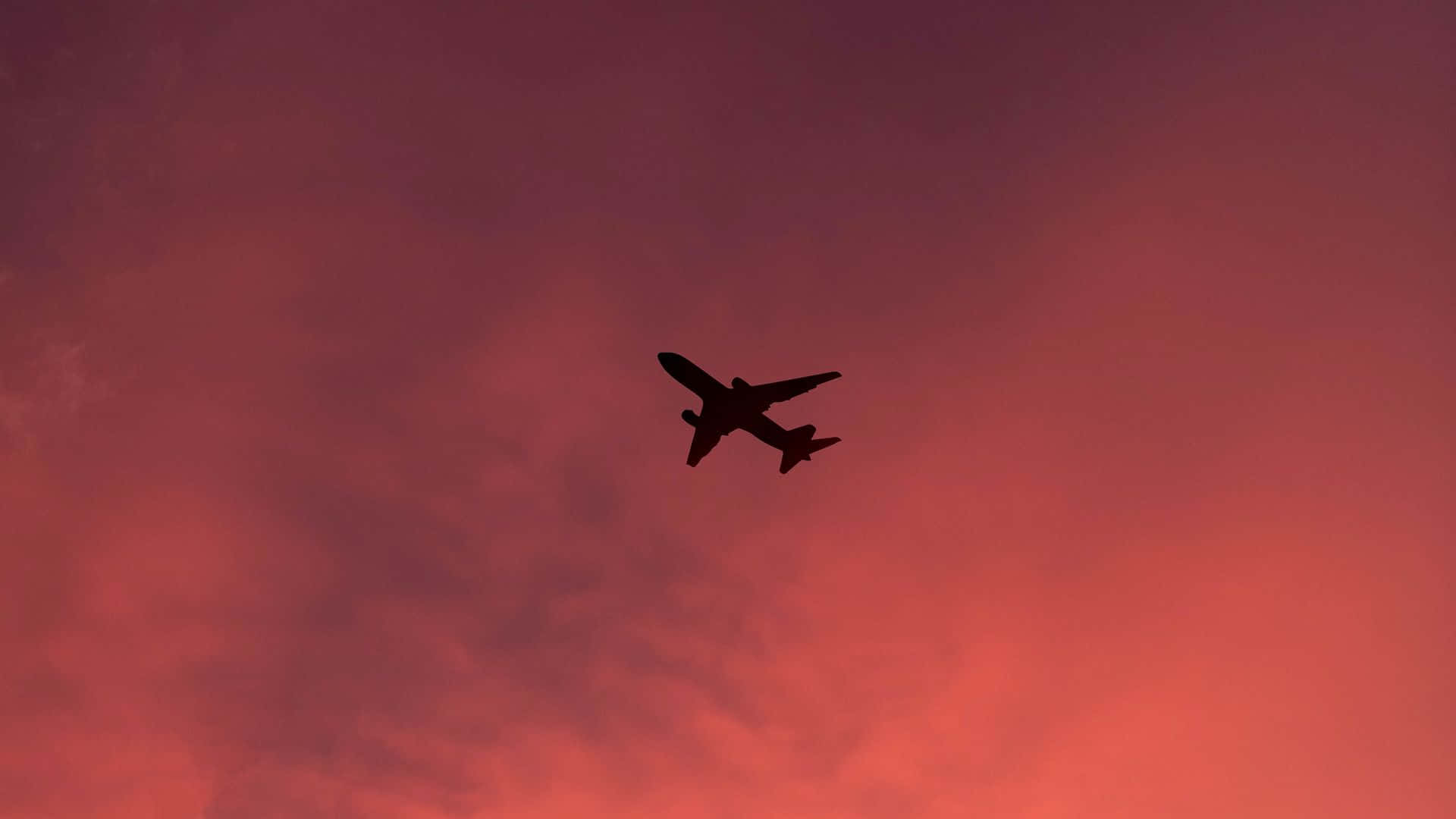 飛機在鮮豔的紅紫日落天空背景下飛行。