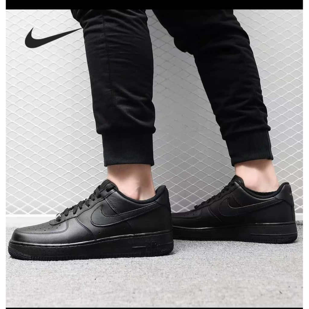 灰色地毯上的黑色Nike Air Force 1運動鞋和黑色慢跑褲。