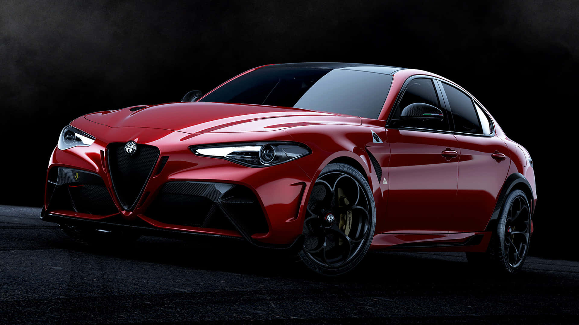體驗駕駛Alfa Romeo的刺激感 壁紙 — 一輛光亮的紅色 Alfa Romeo 運動轎車在戲劇性的工作室燈光下，在黑暗煙霧背景中閃耀。