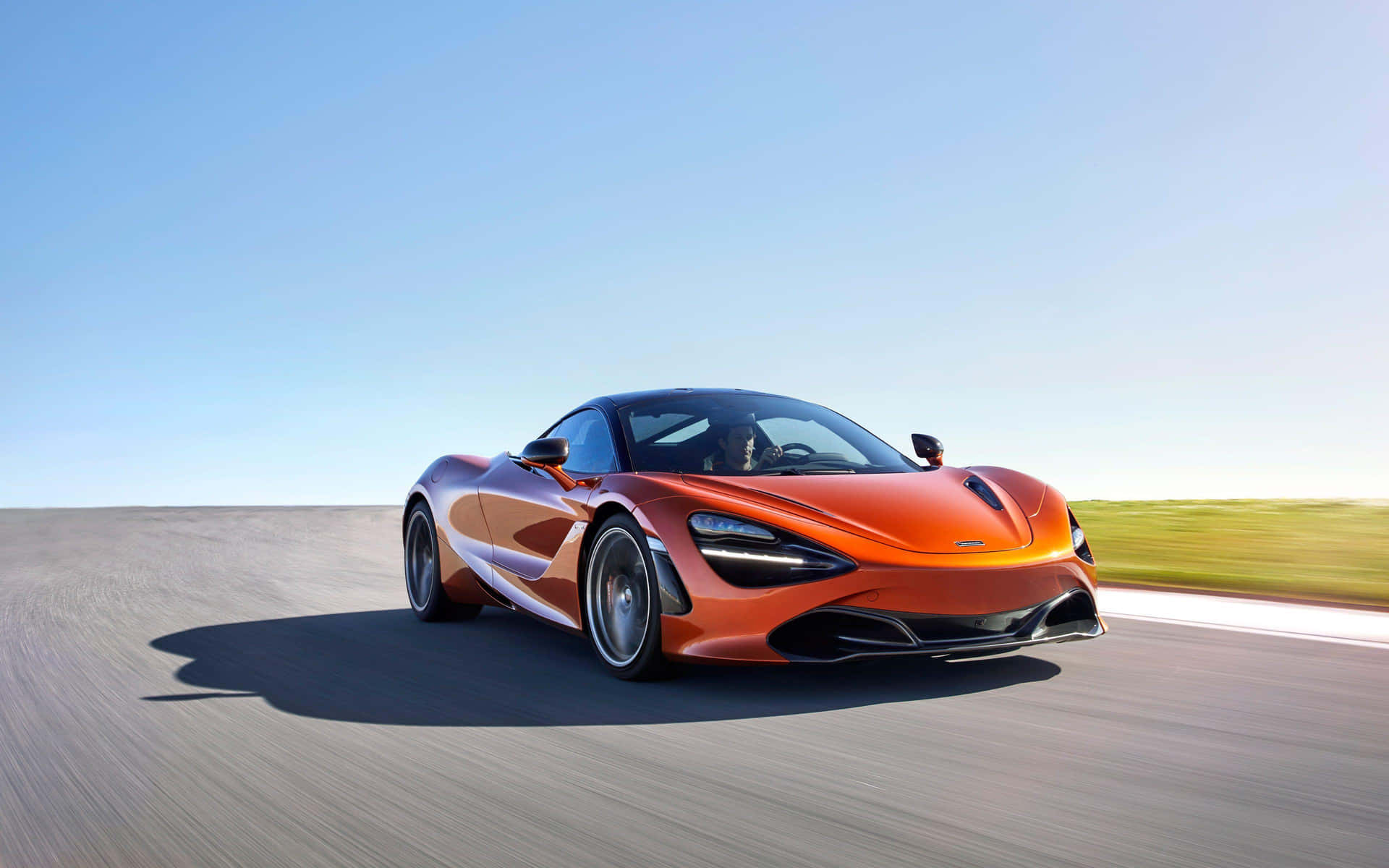 橙色McLaren跑車在日落時分的沙漠公路上疾馳。