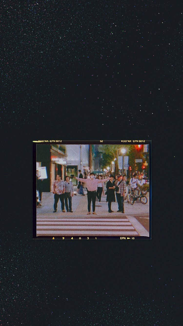 一個人在夜晚的城市人行橫道上張開雙臂，星空下。