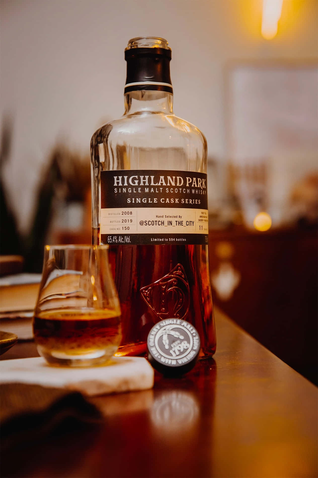 一瓶Highland Park威士忌和一個杯子放在木製吧檯上。