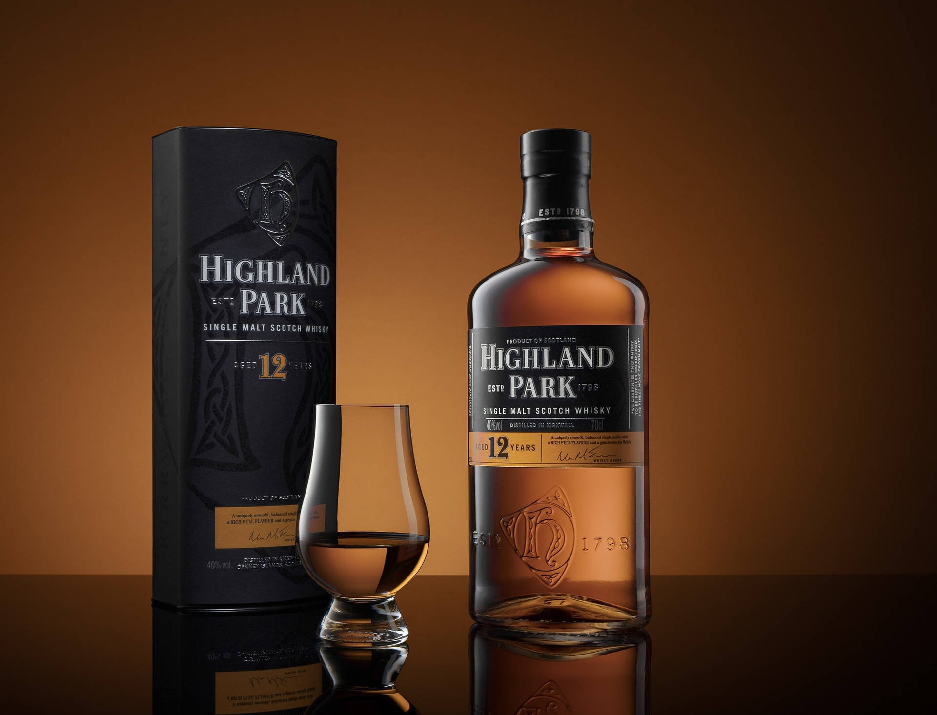 Highland Park 12 年威士忌瓶，附玻璃杯和盒子，置於反射表面。