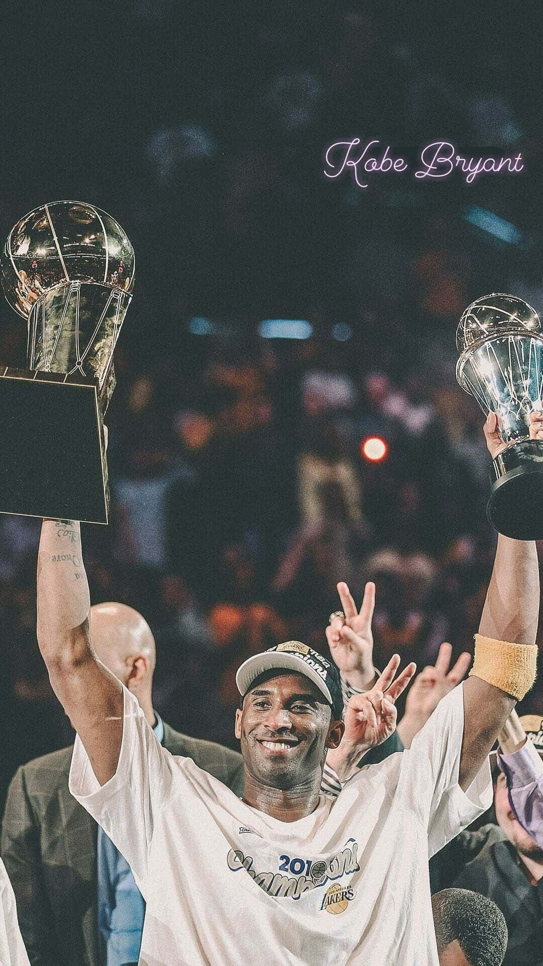 科比· Bryant 桌布 壁紙 — 高比拜仁在擠滿觀眾的場館中，高舉兩個NBA冠軍獎盃，露出勝利的笑容。