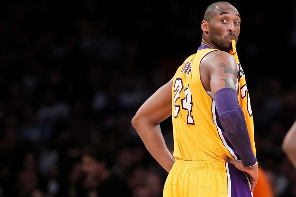 Mamba Mentality 桌布 壁紙 — 高比拜仁身穿黃色湖人24號球衣，雙手叉腰，在籃球比賽中回頭觀望。
