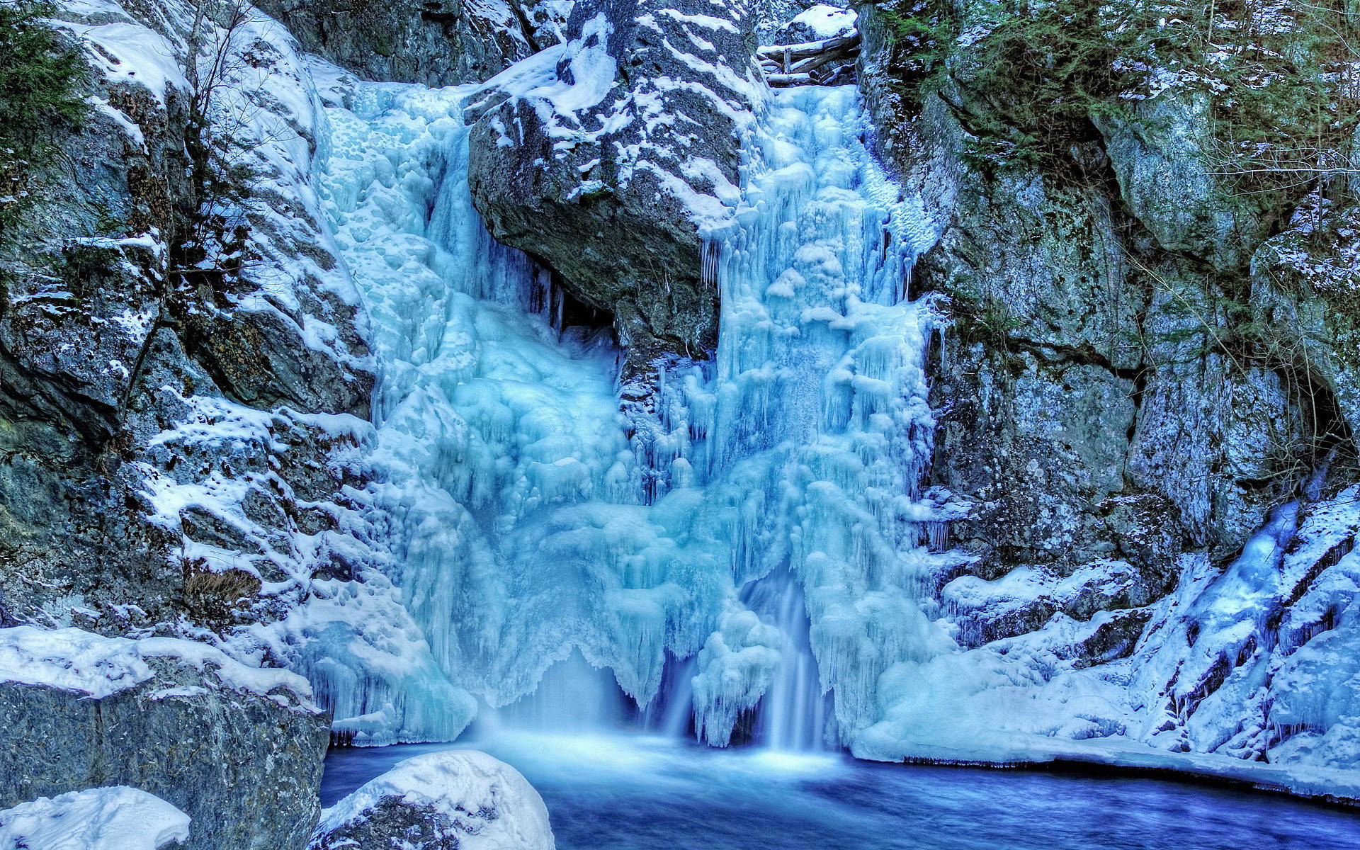 冰凍瀑布，冰藍色的水流過積雪覆蓋的岩石。