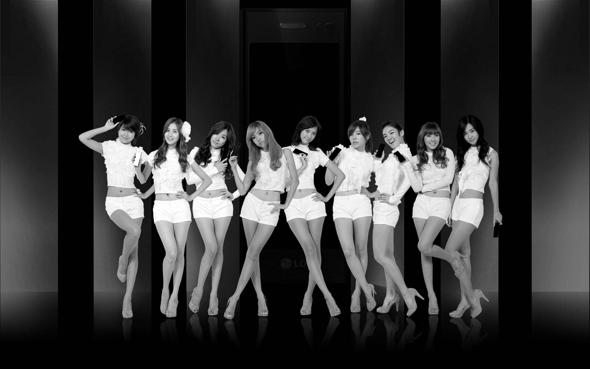 高清少女時代《Chocolate Love》專輯寫真 壁紙 — 八位身穿白色服裝的女性在時尚的黑白工作室中自信地站在巨型電話前擺姿勢。