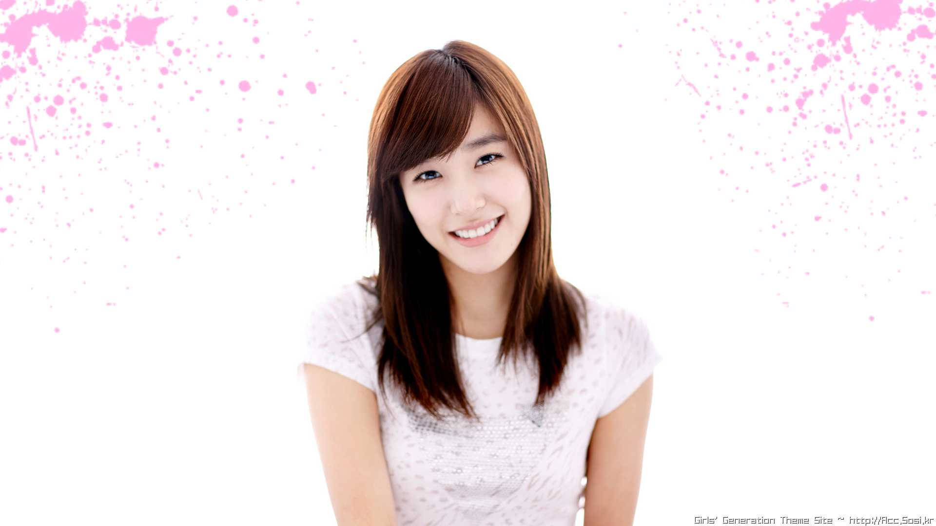 高清少女時代 Tiffany 微笑瞬間 壁紙 — 一位微笑的年輕女性，棕色頭髮，穿著白色上衣，背景是明亮的白色，帶有粉紅色油漆飛濺。