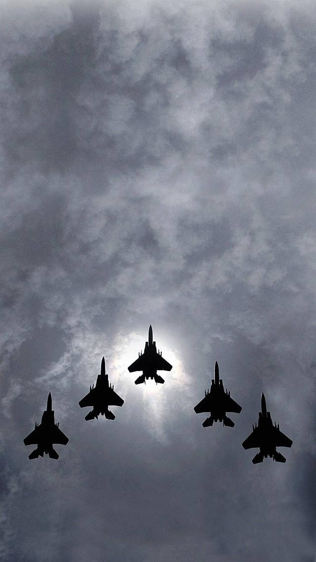 五架戰鬥機在多雲天空中以編隊飛行，太陽在背後。