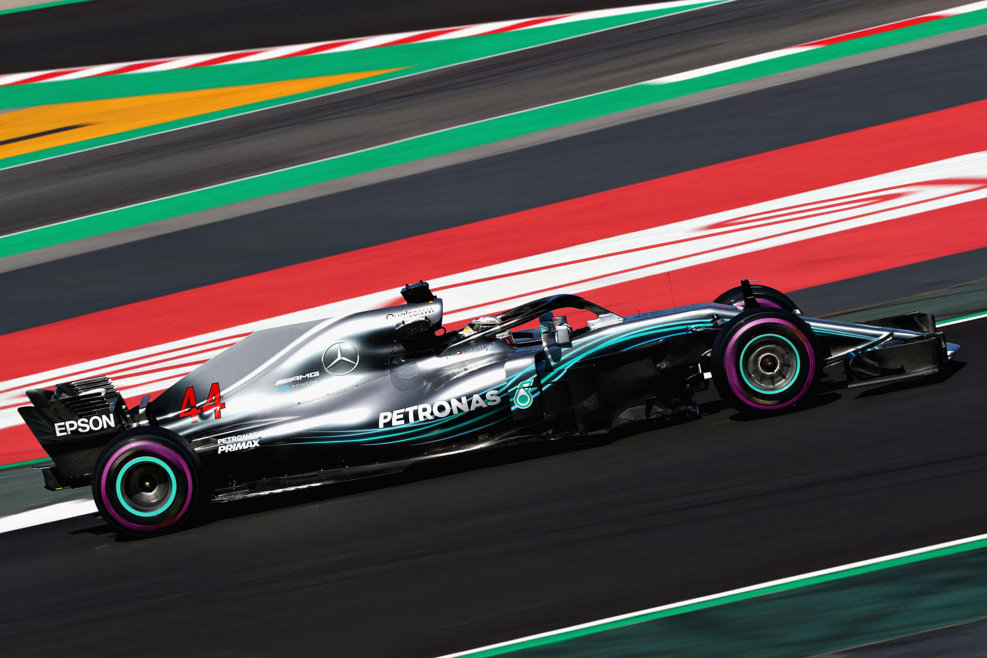 銀色和藍綠色的 Formula 1 賽車在色彩繽紛的路緣賽道上疾馳。