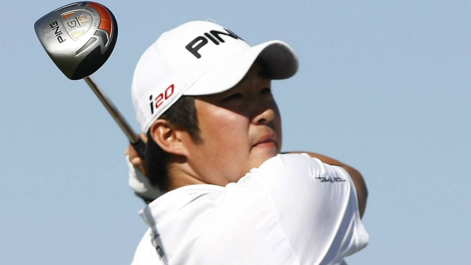 高爾夫球手約翰·胡 Chennai Open 2022 壁紙 — 一位戴白色帽子和穿白色襯衫的高爾夫球手，在晴朗的藍天下揮動PING開球桿。