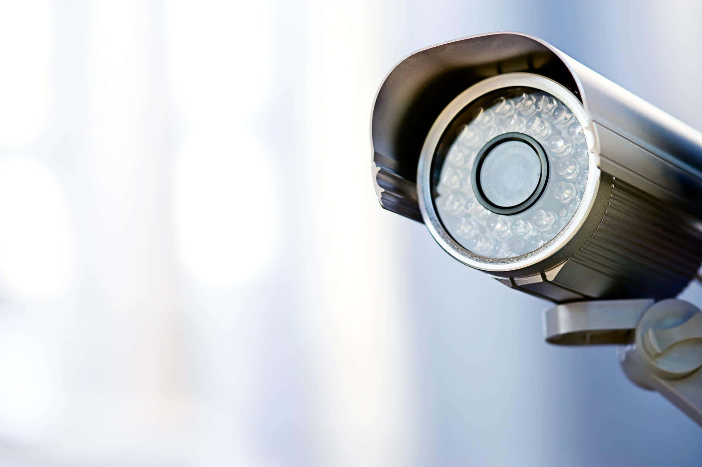 高畫質 CCTV 安全攝影機 壁紙 — 銀色閉路電視攝影機特寫，帶有LED燈，背景明亮模糊。