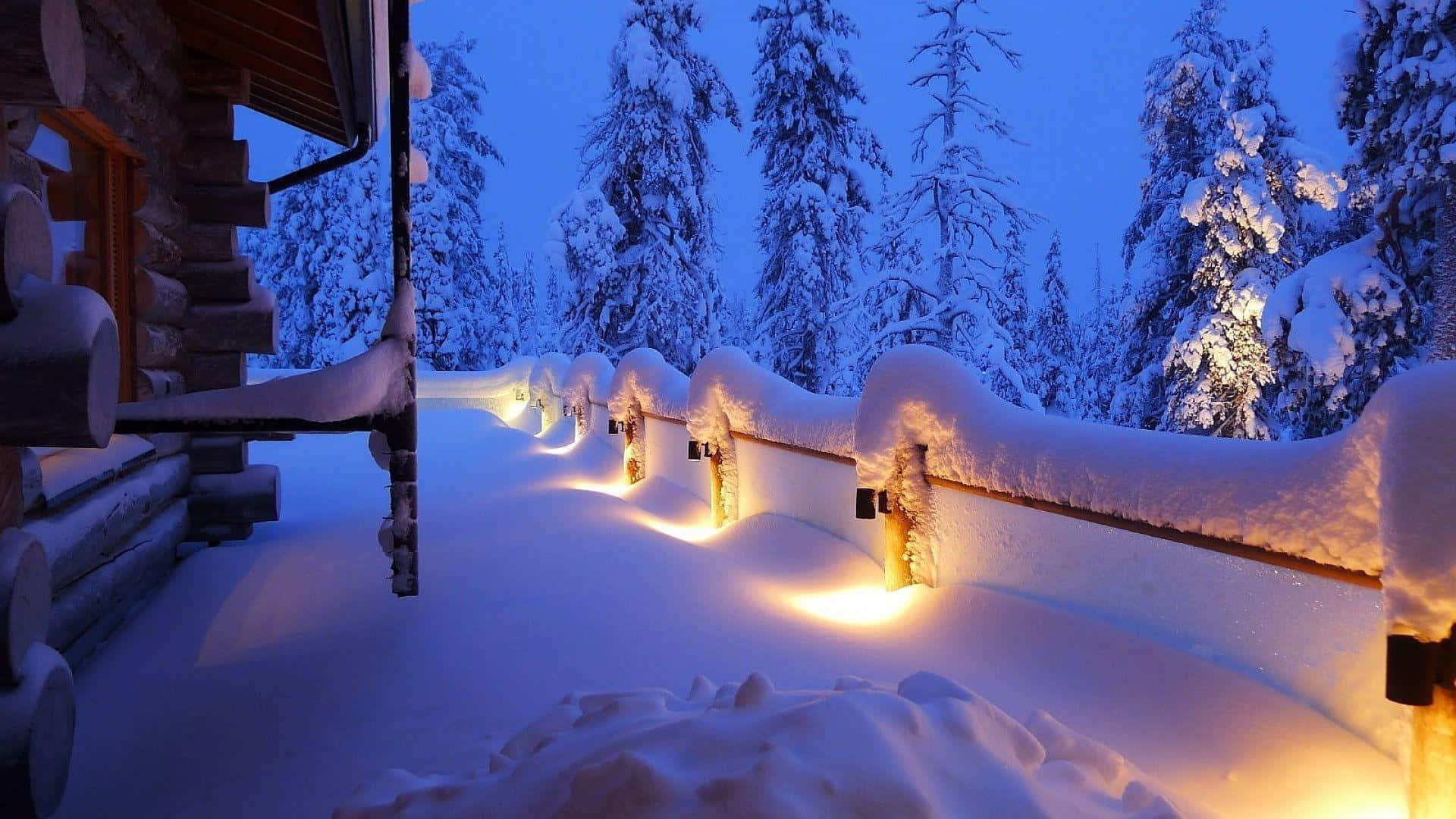 高畫質冬日暖意風景 壁紙 — 一個被雪覆蓋的木屋門廊在串燈下溫暖地發光，背景是黃昏時深藍色的冬季森林。