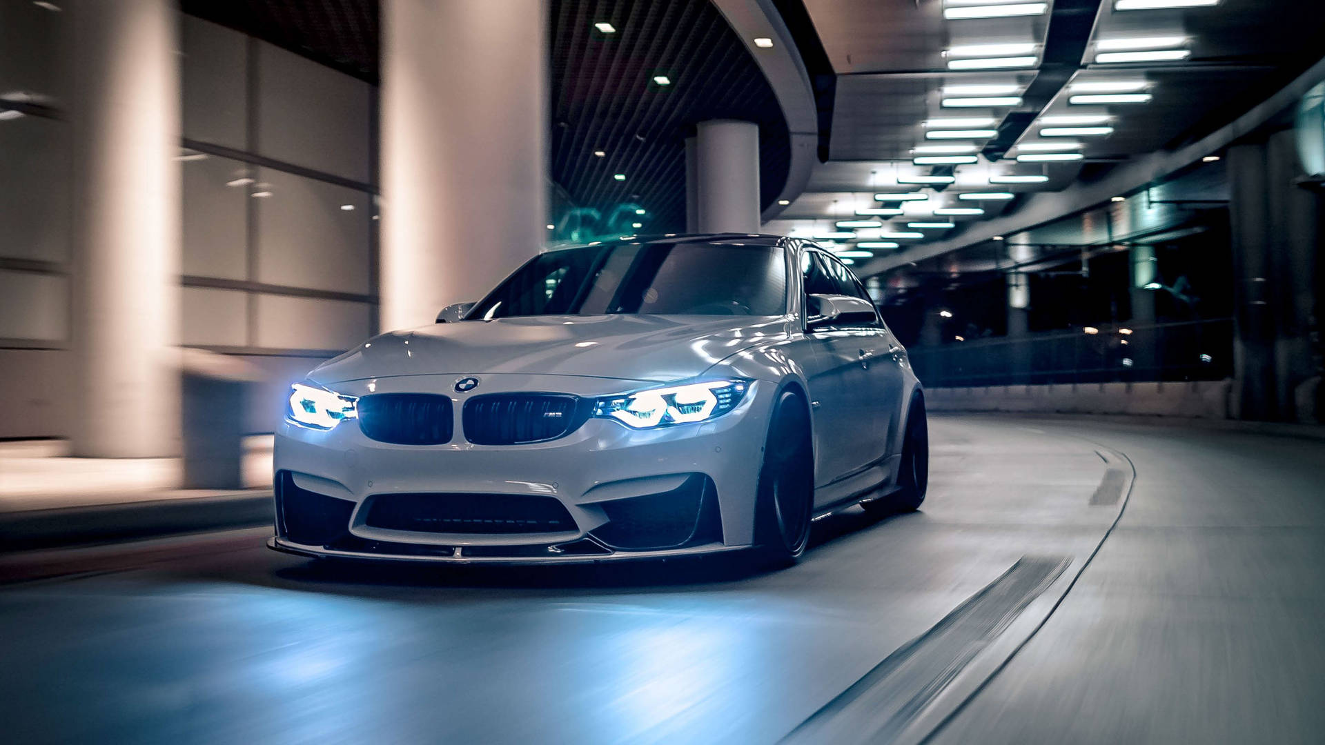 銀色BMW M3在夜間現代隧道中飄移，車頭燈發光。