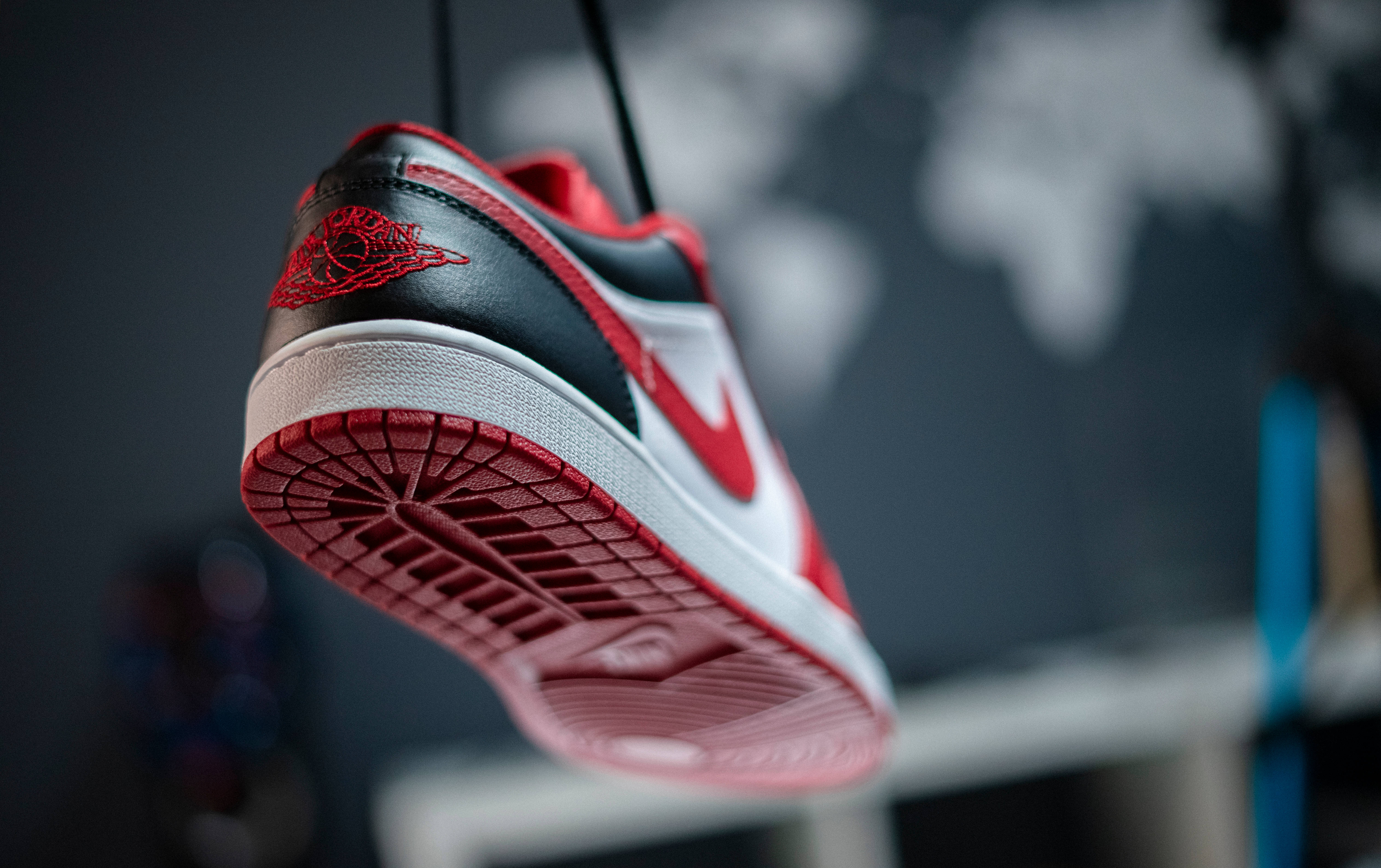 高畫質籃球Nike球鞋 壁紙 — 一雙紅、黑、白色的Jordan運動鞋懸掛在模糊的世界地圖背景前。