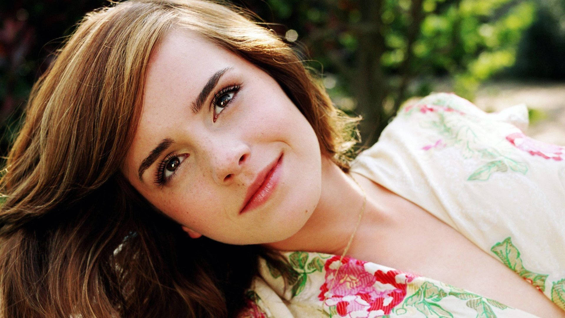 有雀斑的年輕女性穿著花卉上衣在陽光下戶外微笑。