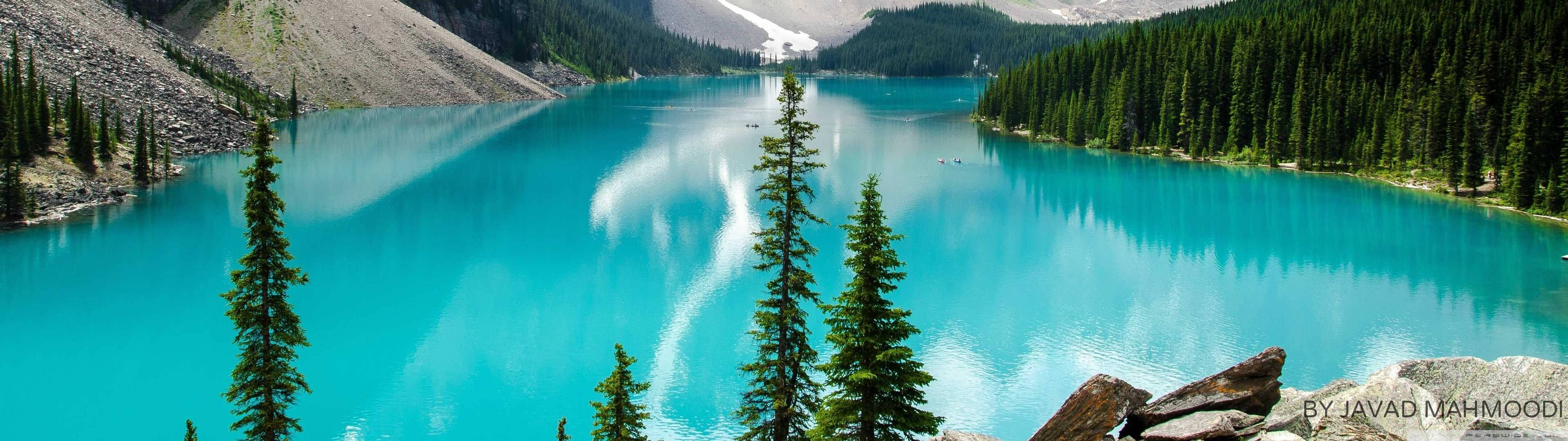 碧綠的高山湖泊，周圍環繞著常綠森林和白雪覆蓋的山峰。