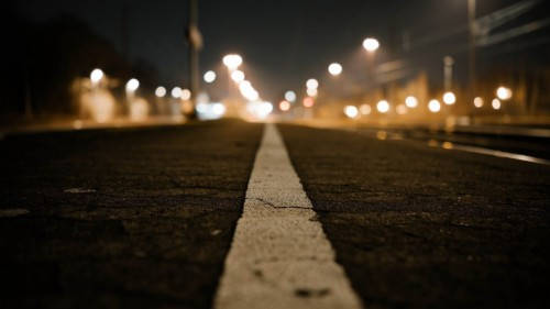 夜間道路，白色線條，模糊的街燈在前方。