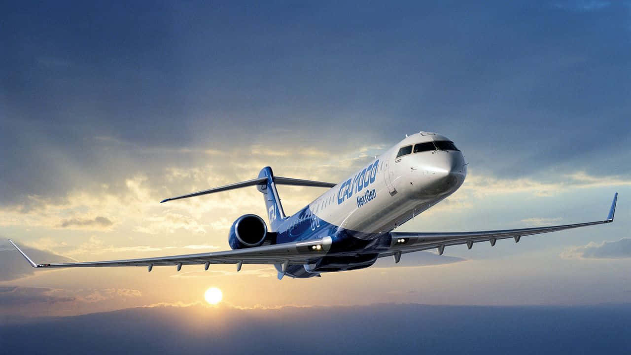 高畫質飛機翱翔雲層之上 壁紙 — 一架 CRJ NextGen 區域噴射機在戲劇性的日落天空下優雅翱翔，伴隨著金色雲彩和下方閃耀的太陽。
