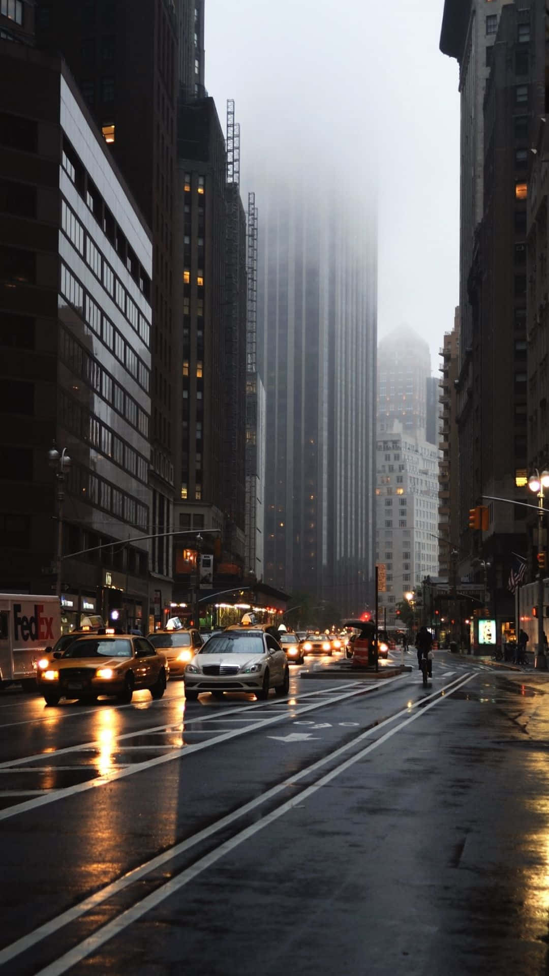黃昏時分的城市街道，下雨，濕漉漉的人行道，霧濛濛的摩天大樓。