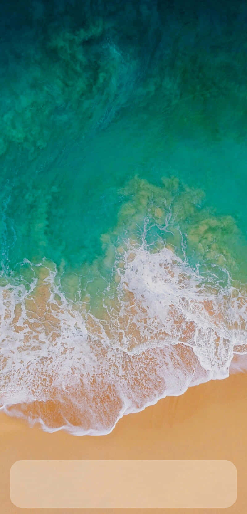 從高空俯瞰，綠松石色的海浪沖刷著金色沙灘。