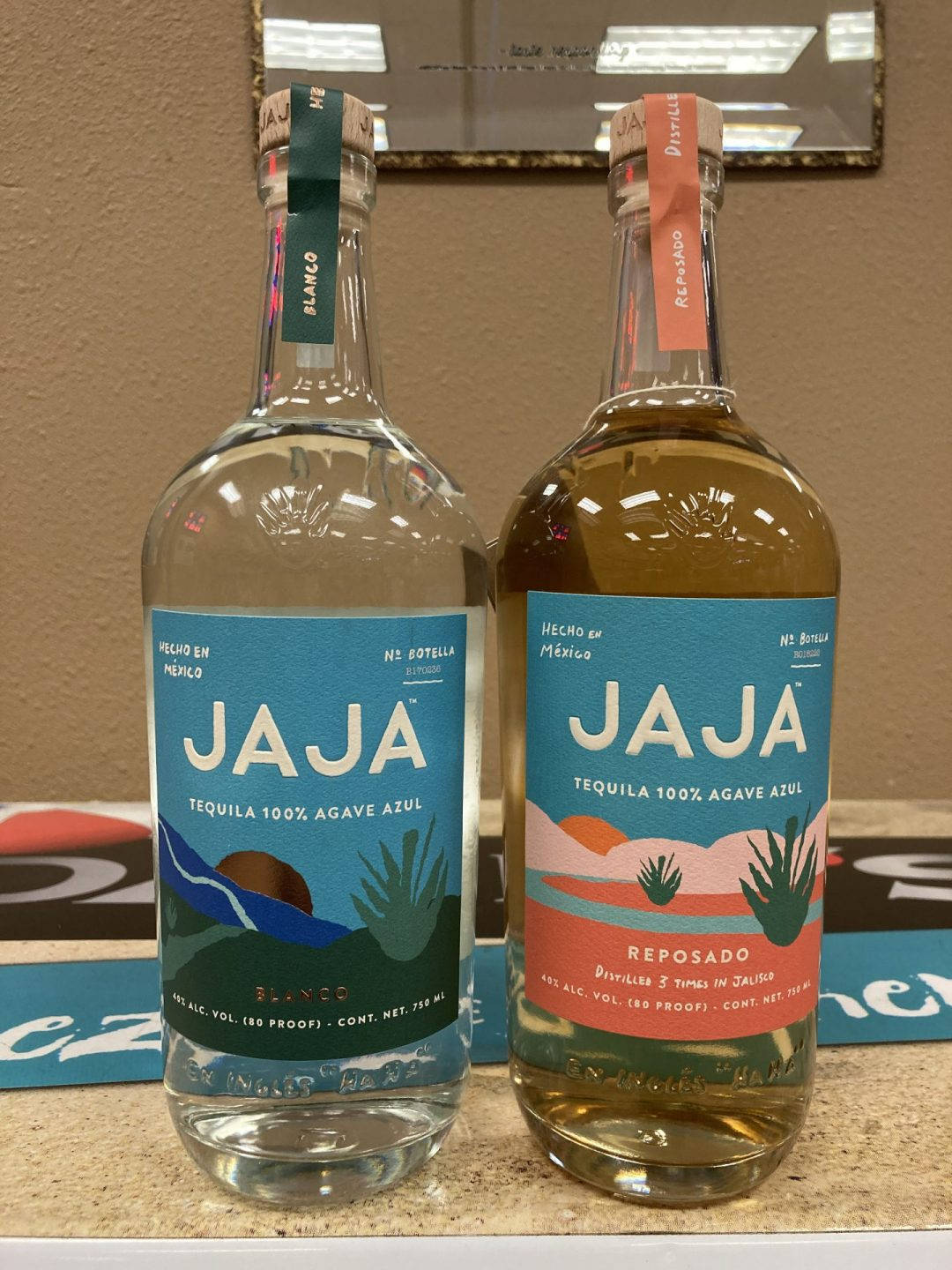 兩瓶Jaja龍舌蘭酒blanco和reposado放在有鏡子背後的檯面上。
