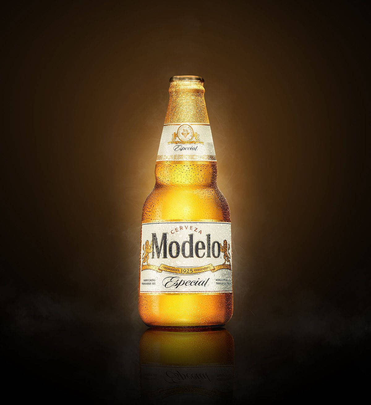 深色反射表面上帶有冷凝水珠的冰凍Modelo啤酒瓶。