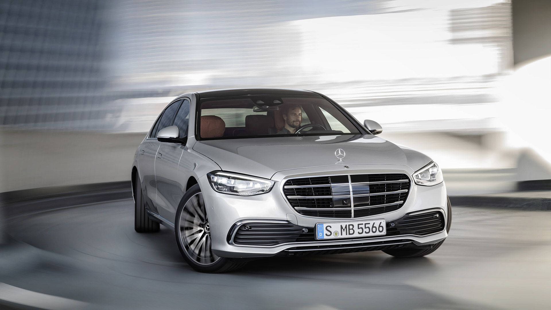銀色 Mercedes S-Class 轎車在現代隧道中疾馳，背景模糊。