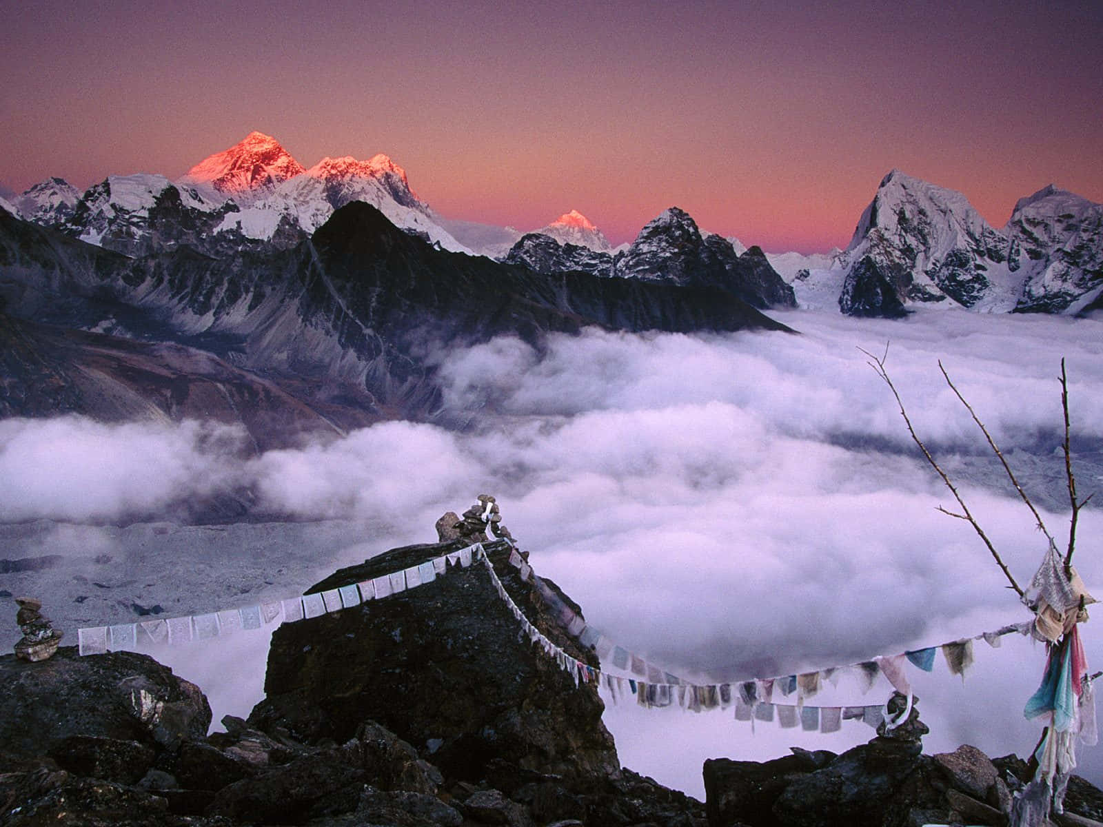 經幡在日出時於雲端之上的山脊飄揚。